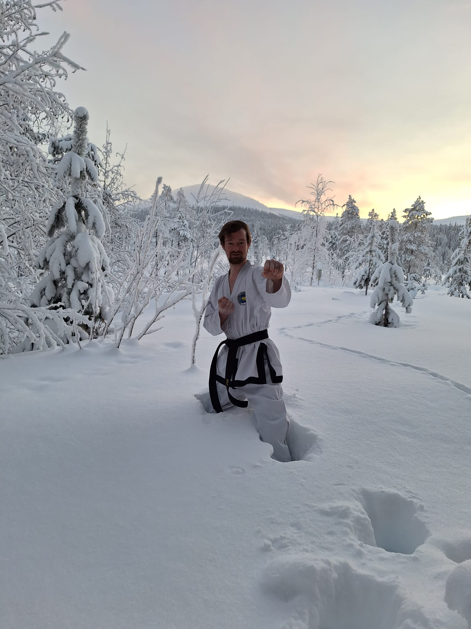 Daan staat in dobok in de sneeuw