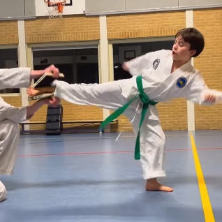 Nick van 12 jaar breekt de zwarte plank met een zijwaartse trap