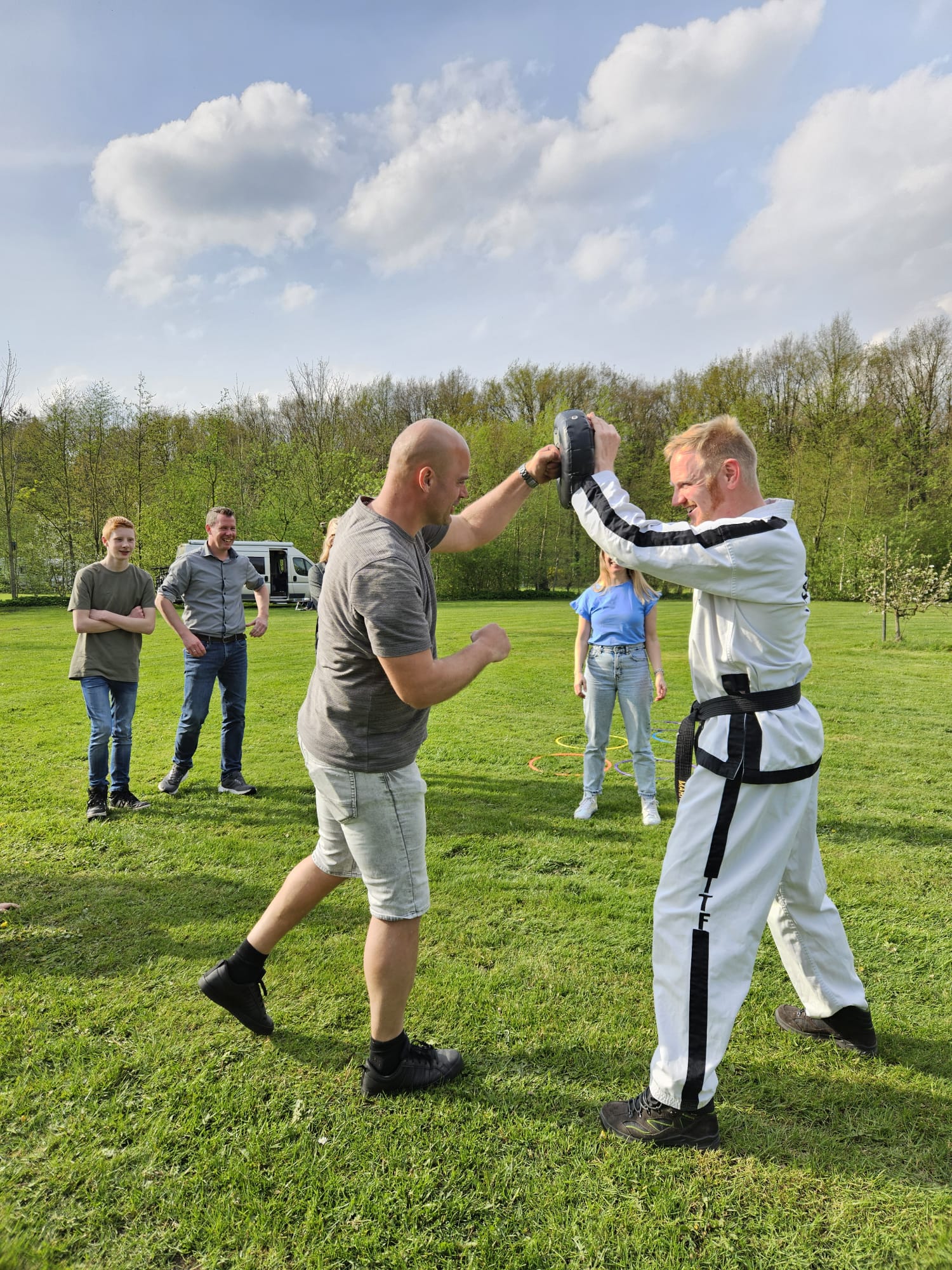 één familielid slaat op een stootkussen dat wordt vastgehouden door instructeur mark in taekwondo kleren één familielid slaat op een stootkussen dat wordt vastgehouden door instructeur mark in taekwondo kleren