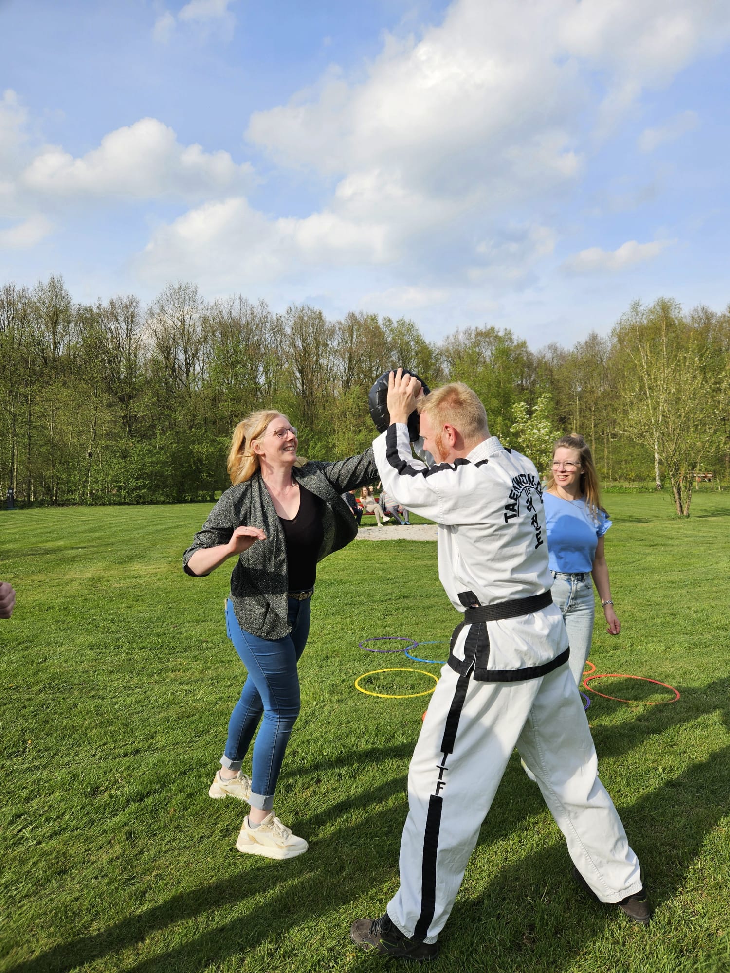 twee familieleden slaan op een stootkussen dat wordt vastgehouden door instructeur mark in taekwondo kleren twee familieleden slaan op een stootkussen dat wordt vastgehouden door instructeur mark in taekwondo kleren